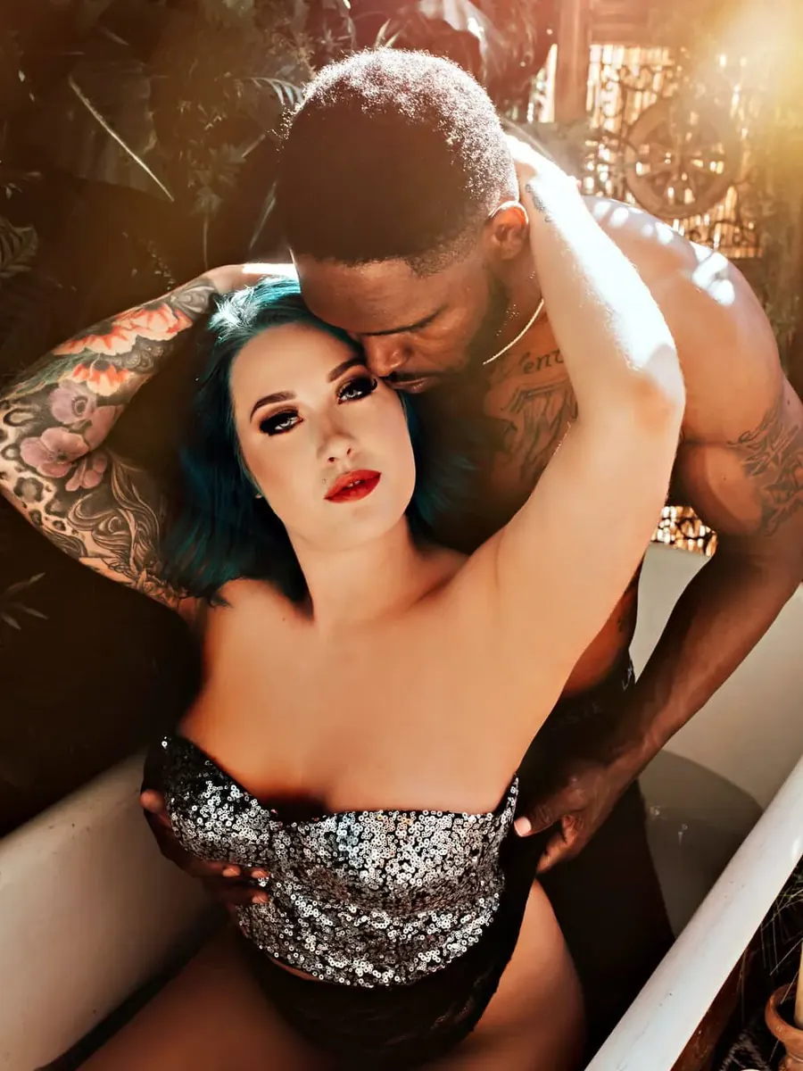 Couple in a clawfoot tub, she with blue hair in a sequined corset