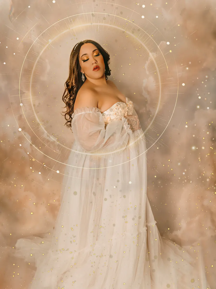 Expectant mother in a flowing ivory gown within a soft golden halo