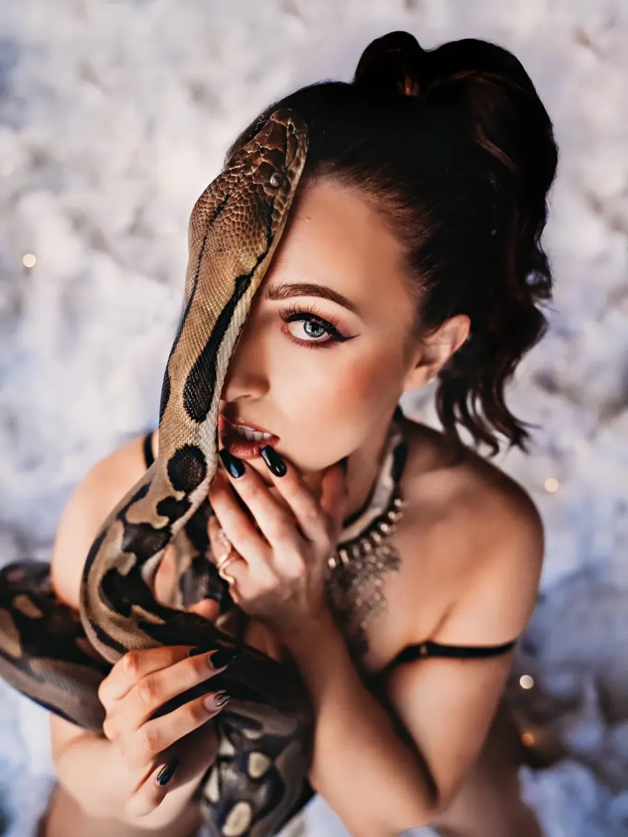 Client with a python draped across her face, gazing up from soft white clouds