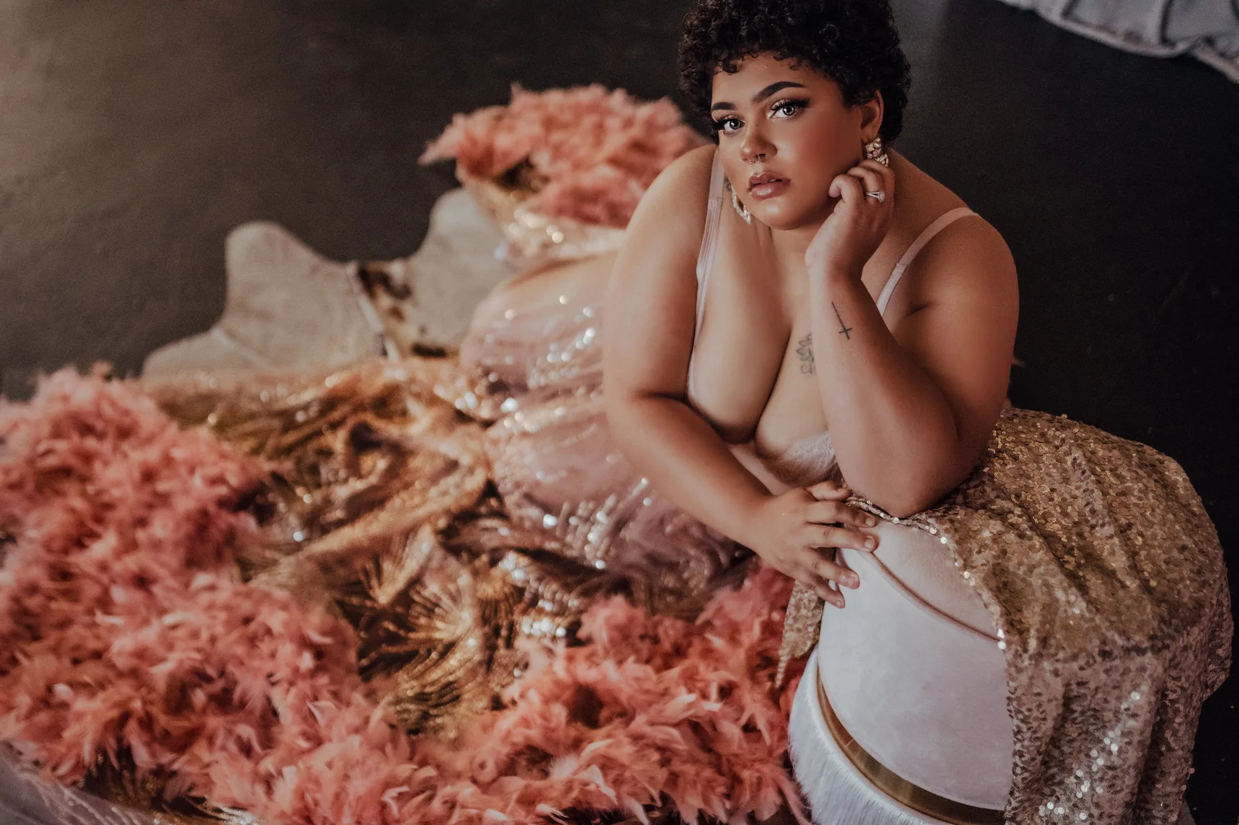 Client in a pink feather and gold sequin skirt, resting her chin on her hand