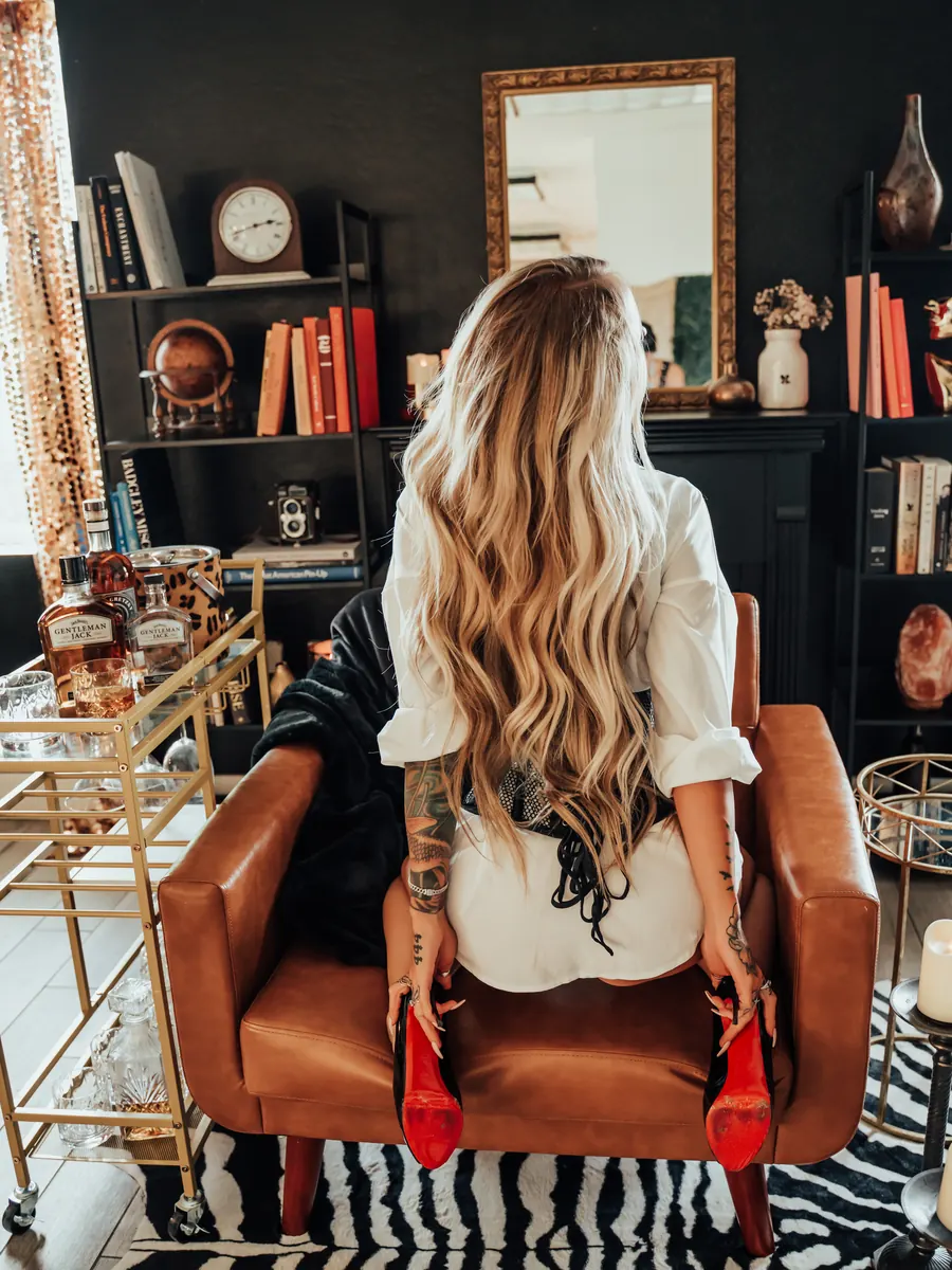 Client from behind in a cognac leather chair facing bookshelves, on a zebra rug
